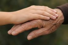 Close-up of a younger hand gently resting on an older hand, symbolising healthy ageing, care and the changing biology of tissues across the lifespan.